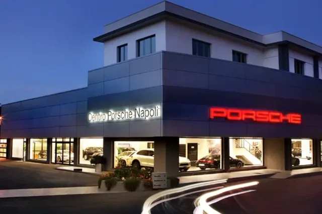Centro Porsche Napoli di notte, con l'insegna rossa e le vetrine illuminate