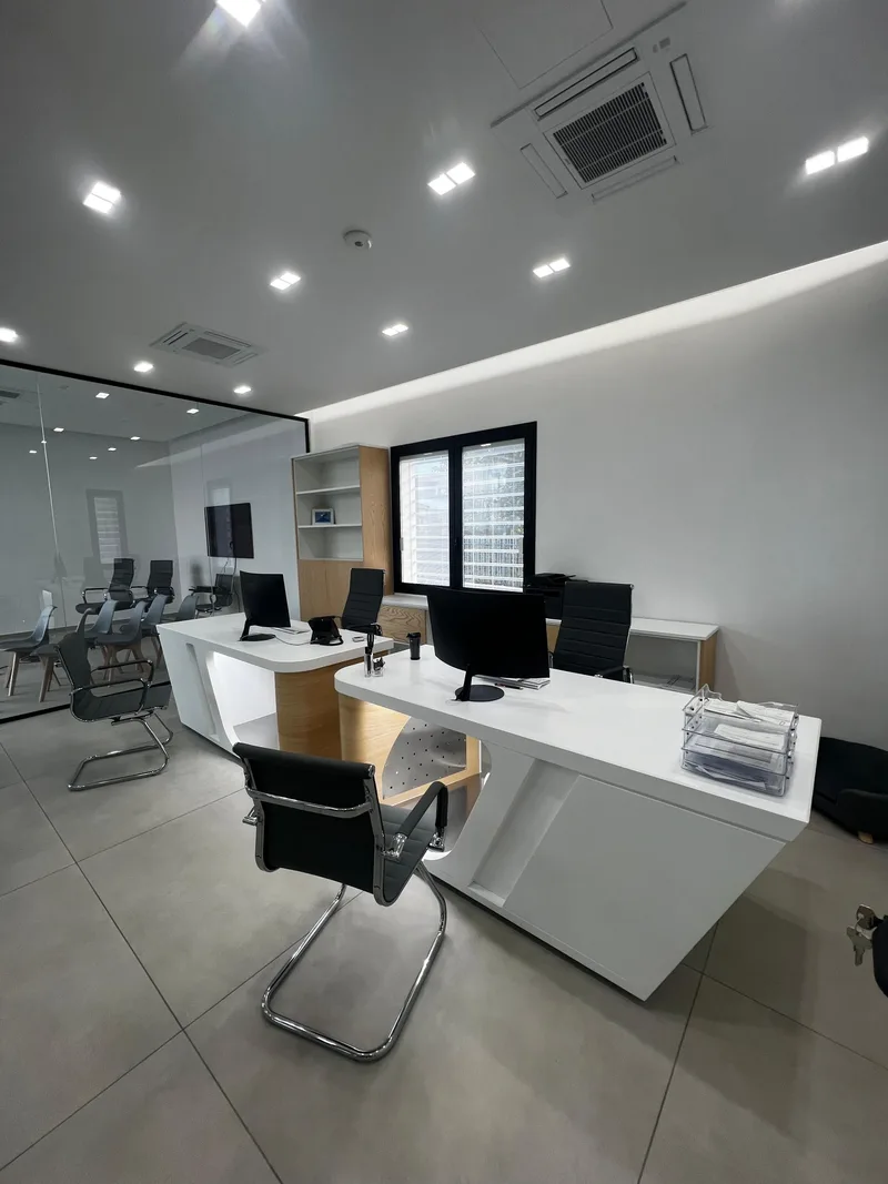 Scrivania di un ufficio con libreria e vista sulla sala riunioni interna