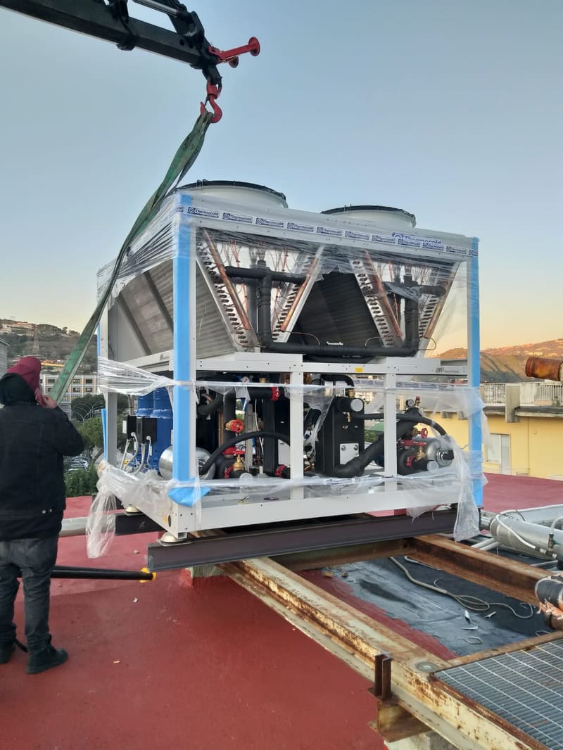 Autogru al lavoro durante il sollevamento di un gruppo frigo su un tetto in Costiera Amalfitana